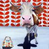 A photographic print of a brown cow with a printed wallpapered background and classic bag.  This cow has literally fallen in love with Orla Kiely.